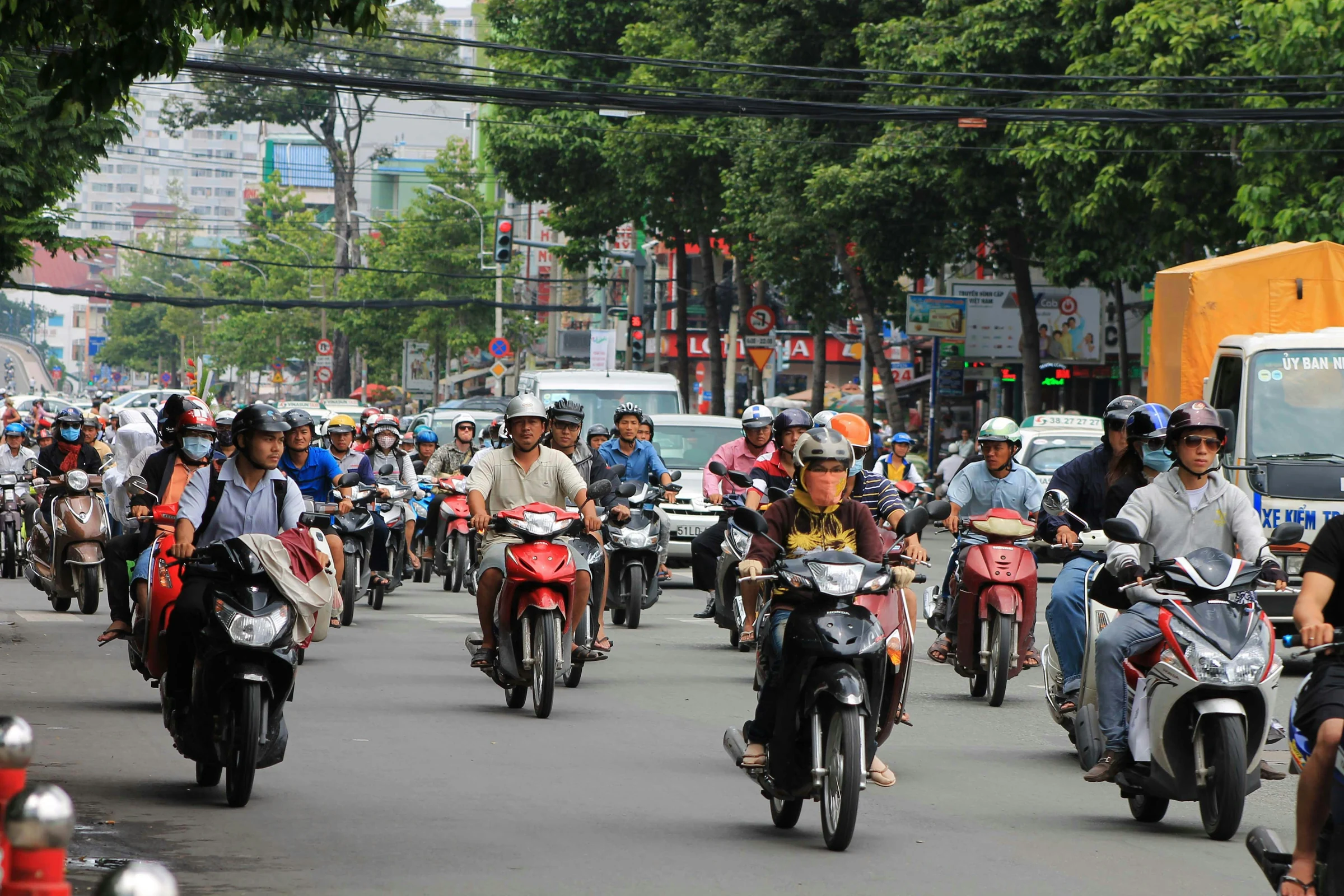 Helmeted scooter and motorbike riders in daytime traffic in Ho Chi Minh City
