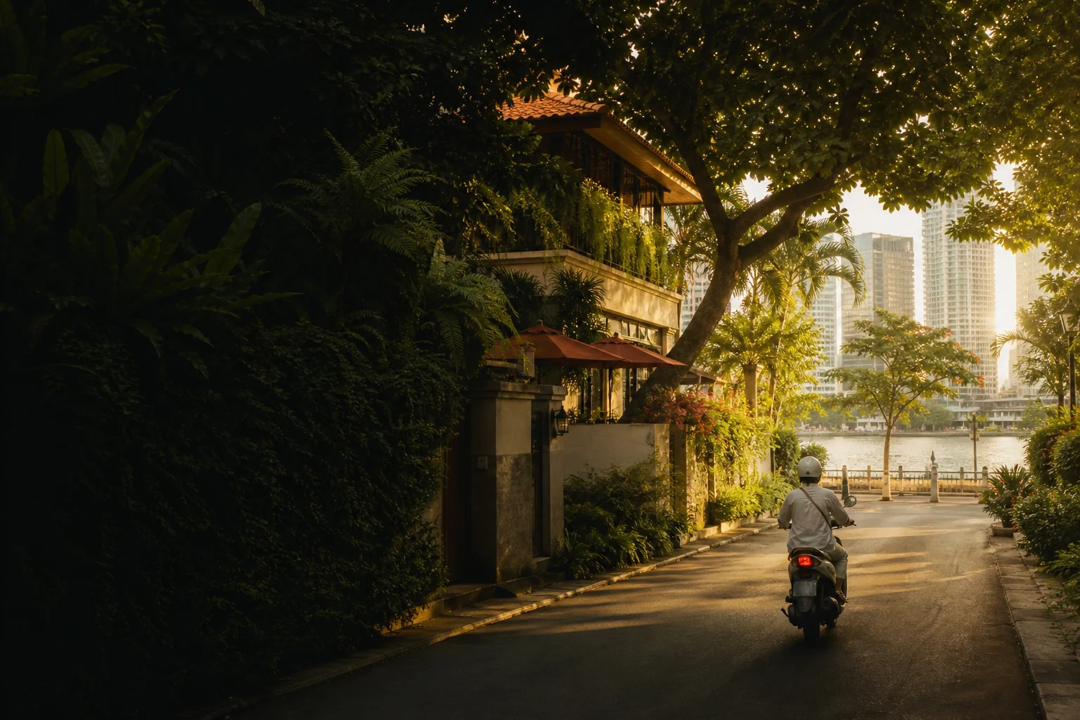Helmeted scooter rider leaving a leafy Thảo Điền lane beside the Saigon River
